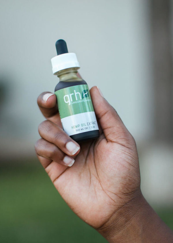 A person holding a bottle of Sublingual/Topical Hemp Oil Extract Tincture 1500mg/32ml
